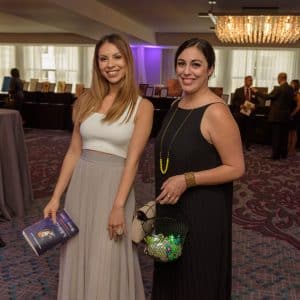 Two female volunteers at Noche Bella selling golden raffle tickets and blinky rings