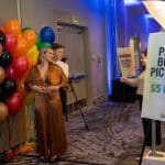 A couple posing in front of many colorful balloons for a photo booth picture at Q Center's SHINE event