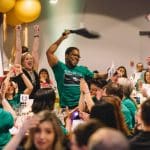 Man celebrating while surrounded by cheering teammates at WorldOregon's fundraising gala